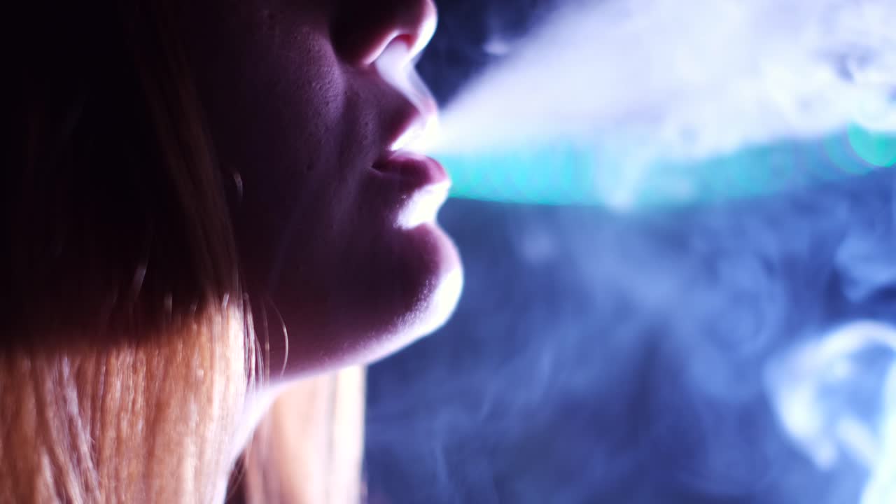 mujer exhalando humo en un club nocturno