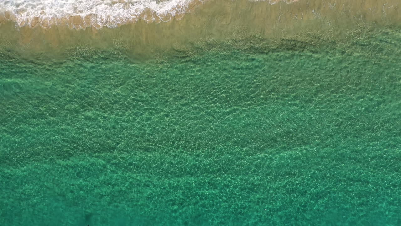 4k drone alejar la toma del mar azul turquesa del océano junto a la orilla de la playa en byron bay, australia