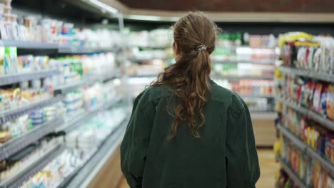 Eine-Frau-In-Einem-Supermarkt,-Die-Einen-Einkaufswagen-Schiebt,-Rückansicht