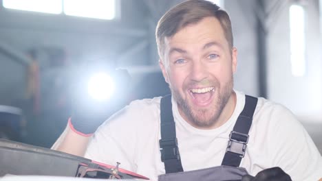 happy mechanic inspecting a car engine with a flashlight