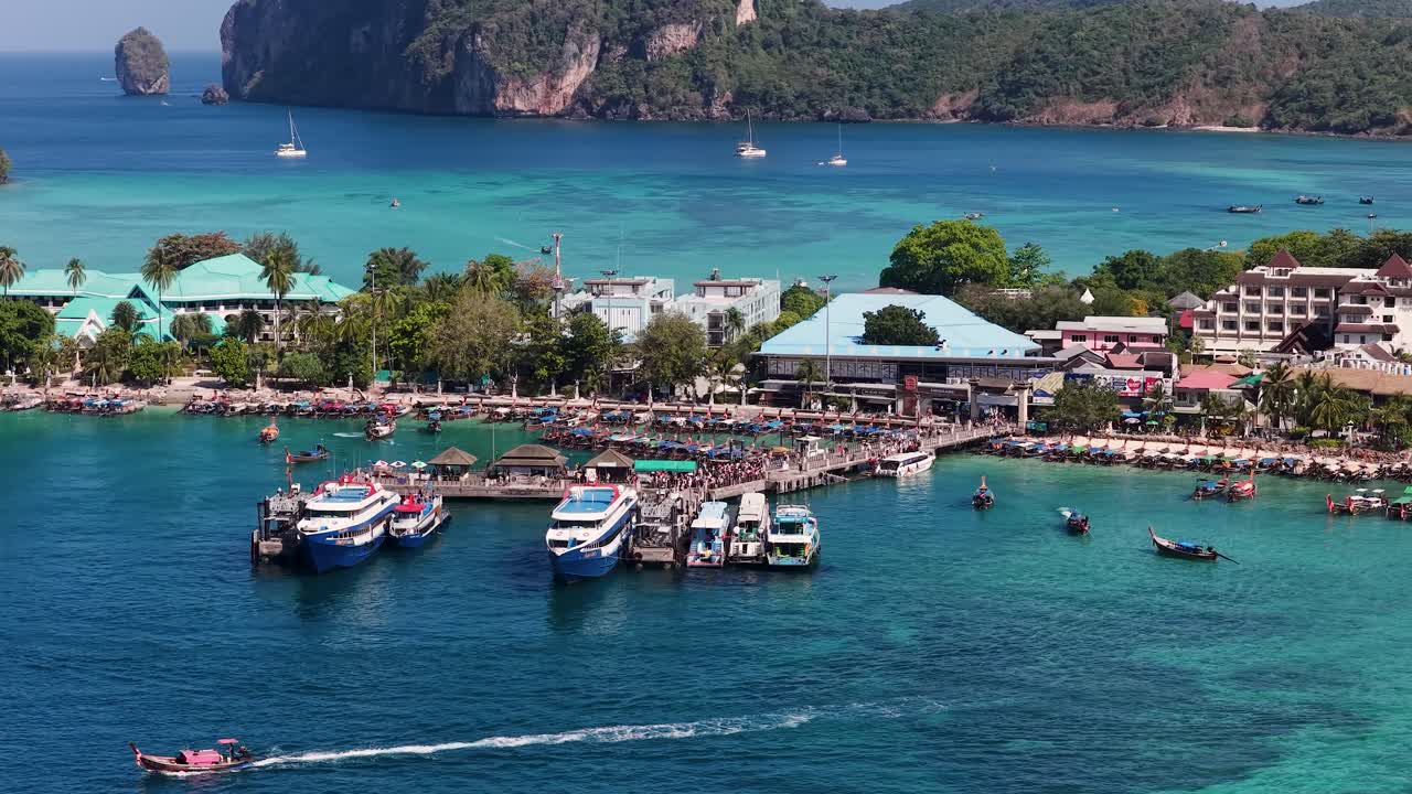 High angle wide shot of a tropical island pier with ferries and longtail boats