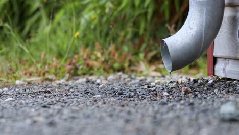 close-up of a downspout draining water onto gravel