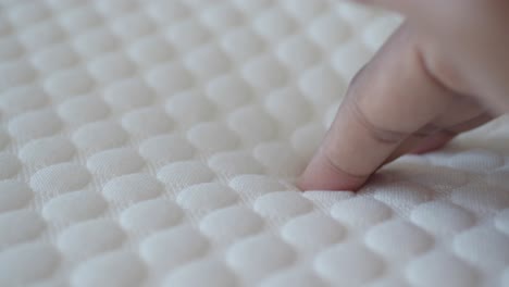 close up of a finger pressing on a white memory foam mattress