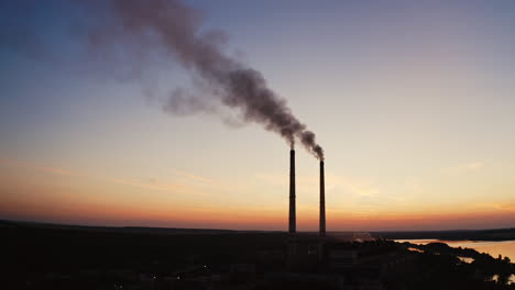 Dirty smoke from industrial pipes over the clear evening sky. Chemical smoke comes out of the pipes of power plant at darkness.