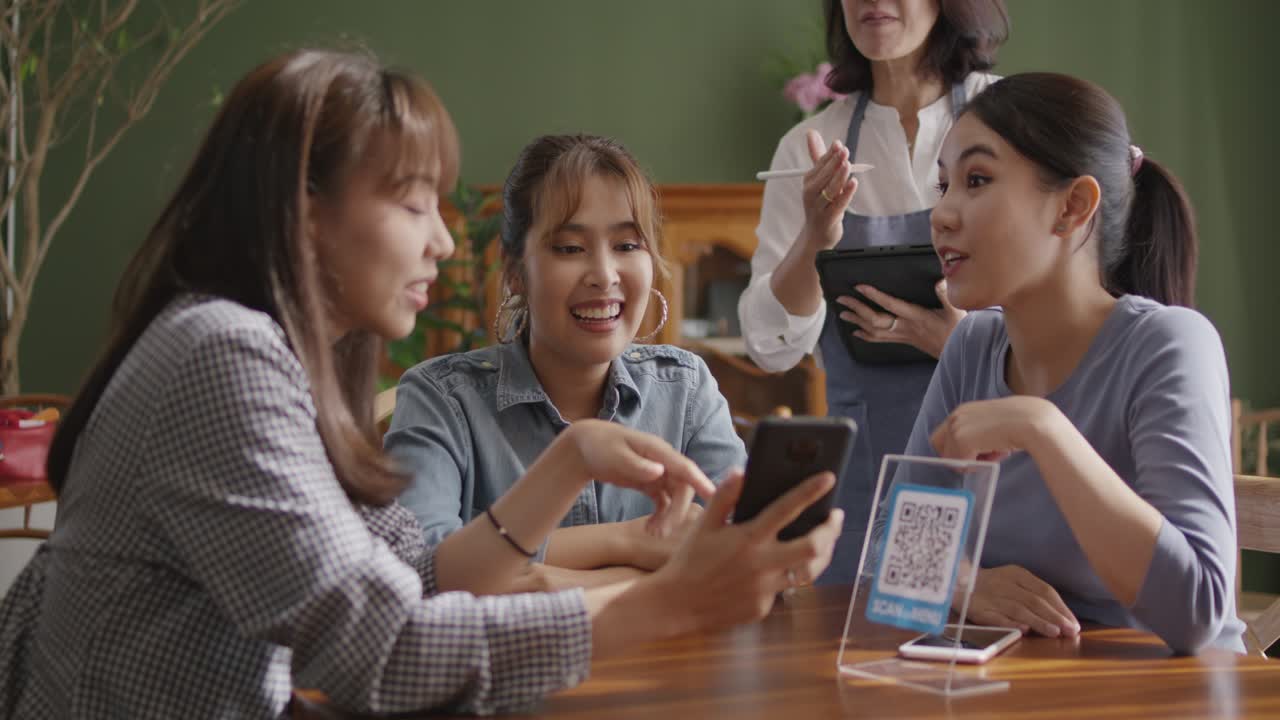 젊은 여성 그룹이 함께 채식주의자 식당에서 디지털 메뉴를 사용합니다.