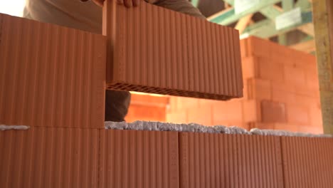 Worker places hollow ceramic bricks to build wall at house construction site
