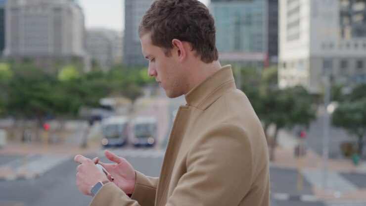portrait young handsome businessman using smartphone taking photos in city on mobile phone camera enjoying urban sightseeing caucasian male commuter slow motion