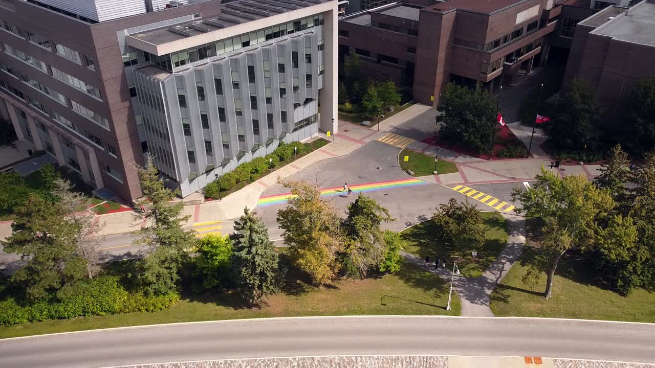 Canadian students walk across pride rainbow crosswalk on Ontario University (Carleton) campus