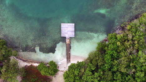 scenic aerial shot above of kid running on a wood dock with blue water of the caribbean sea