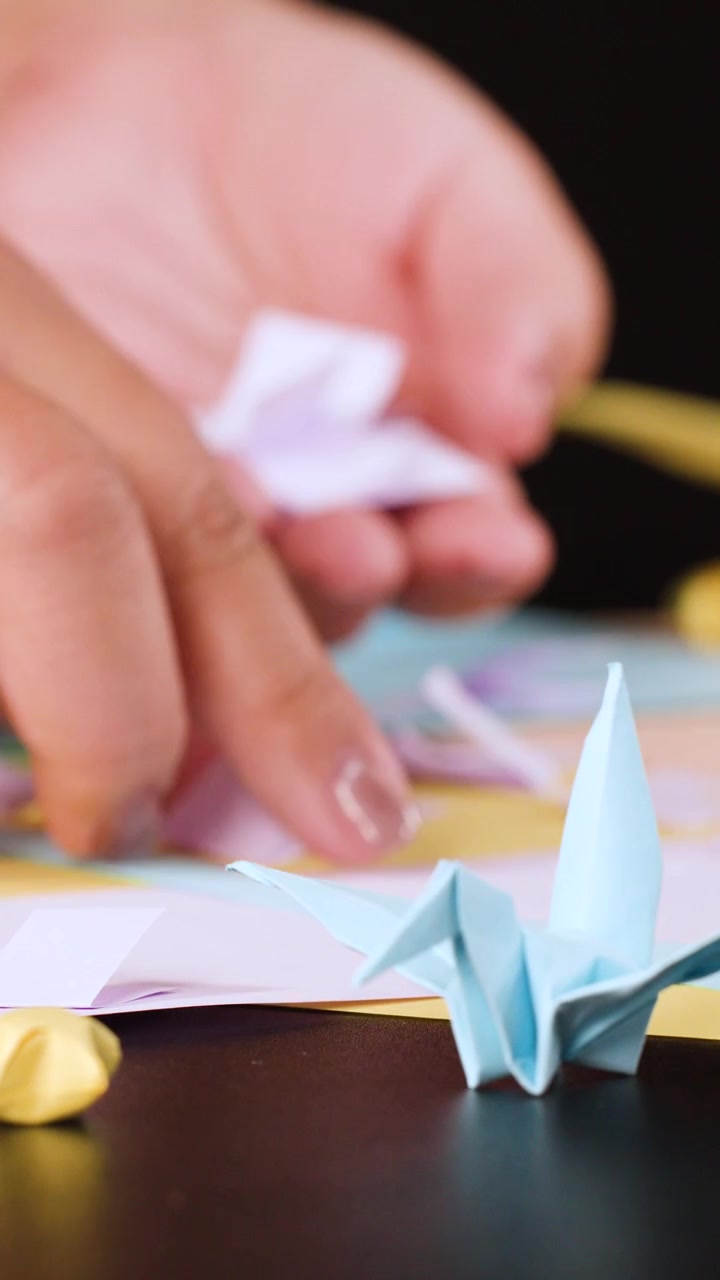 Persona che piega piccoli quadrati di carta per l'origami