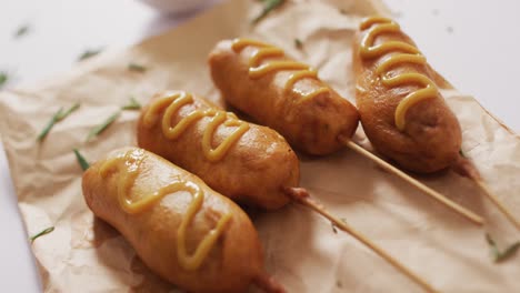 video of corn dogs with dip on a white surface