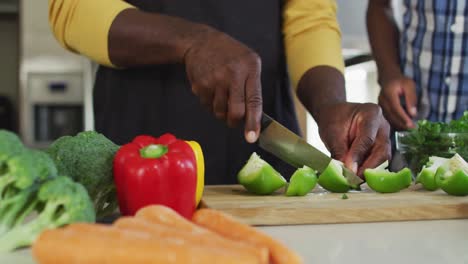 Afroamerikanischer-älterer-Vater-Und-Zwei-Erwachsene-Söhne-Stehen-In-Der-Küche,-Kochen-Abendessen-Und-Reden