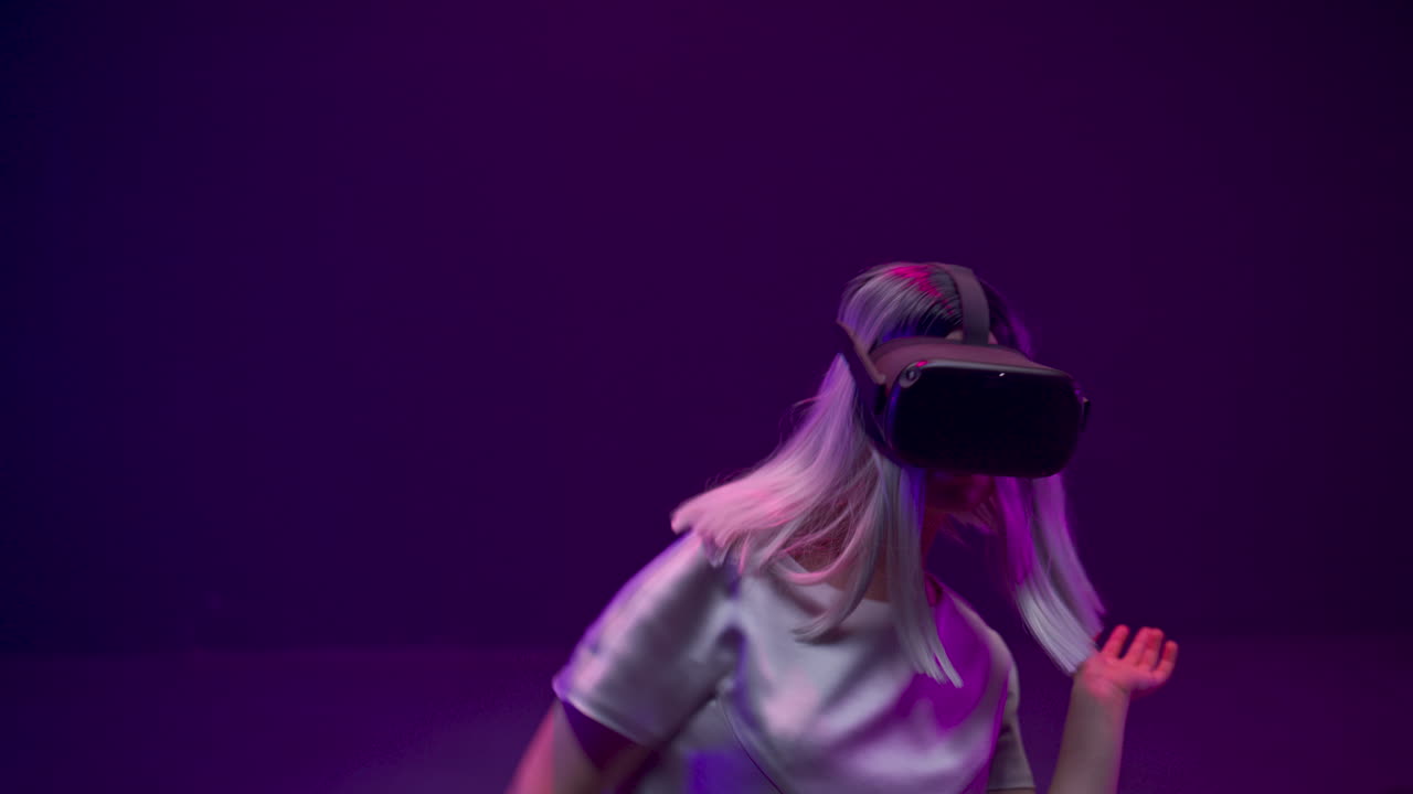una donna bionda che balla con gli occhiali vr alla luce al neon.