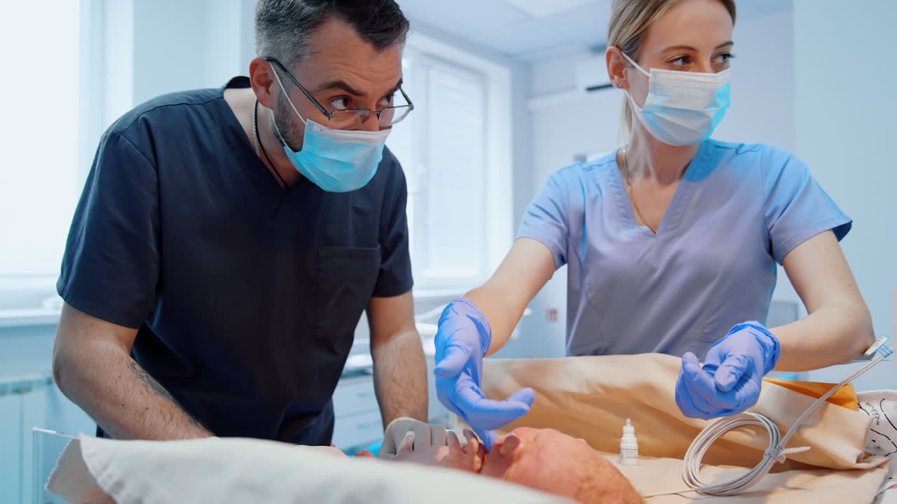 Male pediatrician in blue uniform checks the newborn child. Nurse gives a finger in latex glove to baby.