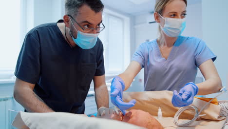 male pediatrician in blue uniform checks the newborn child. nurse gives a finger in latex glove to baby.