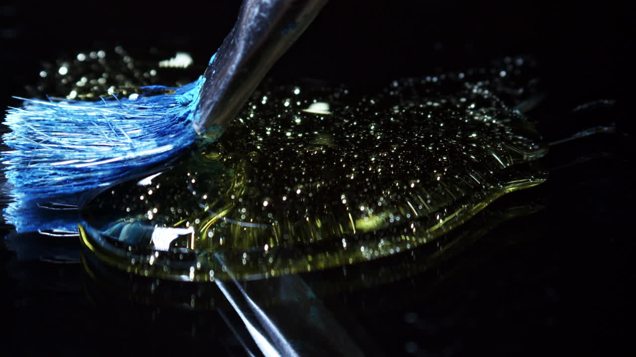 검정색 배경에 있는 금색 액체를 통한 극적인 페인트 브러시 스트로크