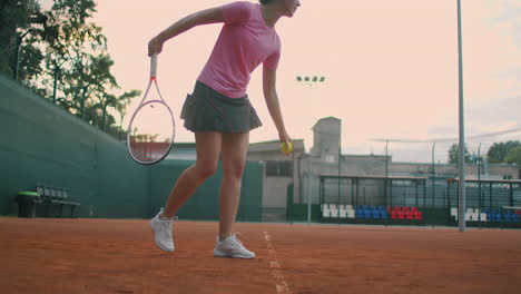 vista a bassa angolazione al rallentatore di una giovane tennista che si prepara a servire una partita di tennis. un'atleta sta colpendo con forza una palla durante la pratica sportiva. filmati di uso commerciale