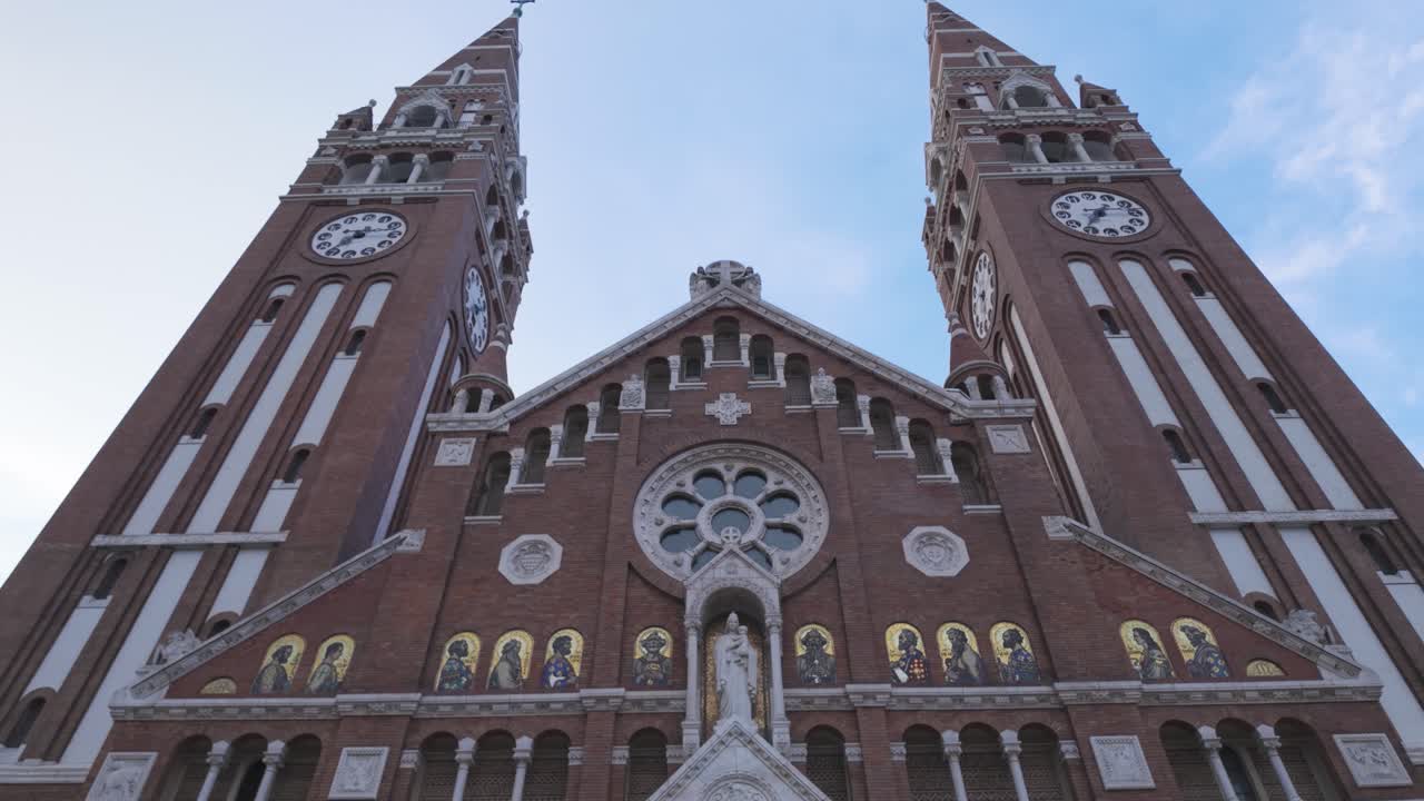 Tilt-up shot of the Votive Church in Szeged, Hungary, revealing the ornate Neo-Romanesque facade and architectural details