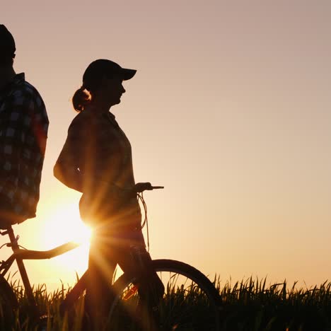 a young couple admires the beautiful scenery at sunset standing near the bike