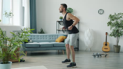 man performing resistance band back workout at home