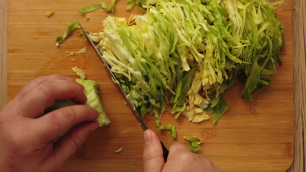 The cook cuts the cabbage on the cutting board.
