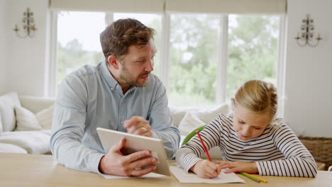 father helping daughter sitting at table with digital tablet home schooling during health pandemic