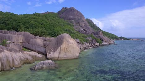 Drohnen-Tracking-Aufnahme-Des-Wunderschönen-Tropischen-Strandes-In-La-Digue,-Seychellen,-Unter-Blauem-Himmel-Mit-Türkisfarbenem-Wasser