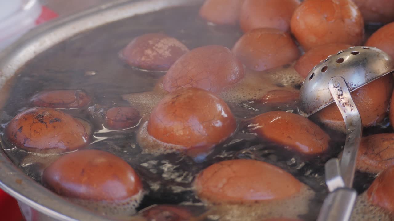 Chinese century eggs or tea egg in boiling water close-up. Chinese egg-based culinary dish made by preserving duck, chicken, or quail eggs in a mixture of clay, ash, salt, quicklime, and rice hulls for several weeks to several months.Korean mayak eggs or mayak gyeran are boiled eggs marinated in a f