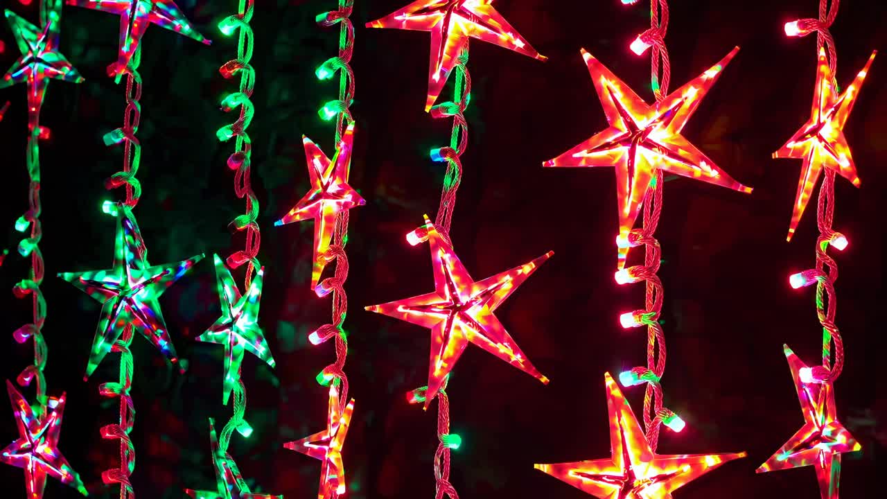 Vibrant close-up video of colorful star-shaped string lights hanging vertically, creating a festive