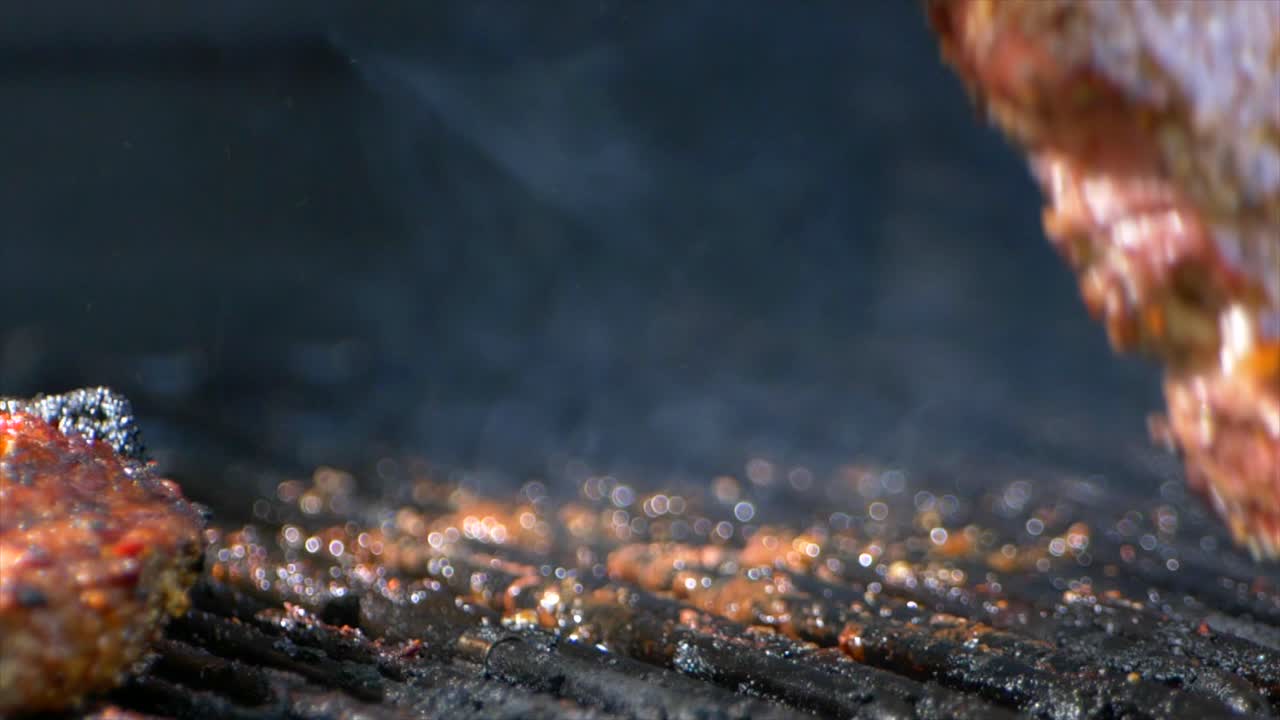 한 쌍의 고기 집게는 그릴에서 거의 익힌 육즙이 많은 립아이 스테이크를 돌립니다.