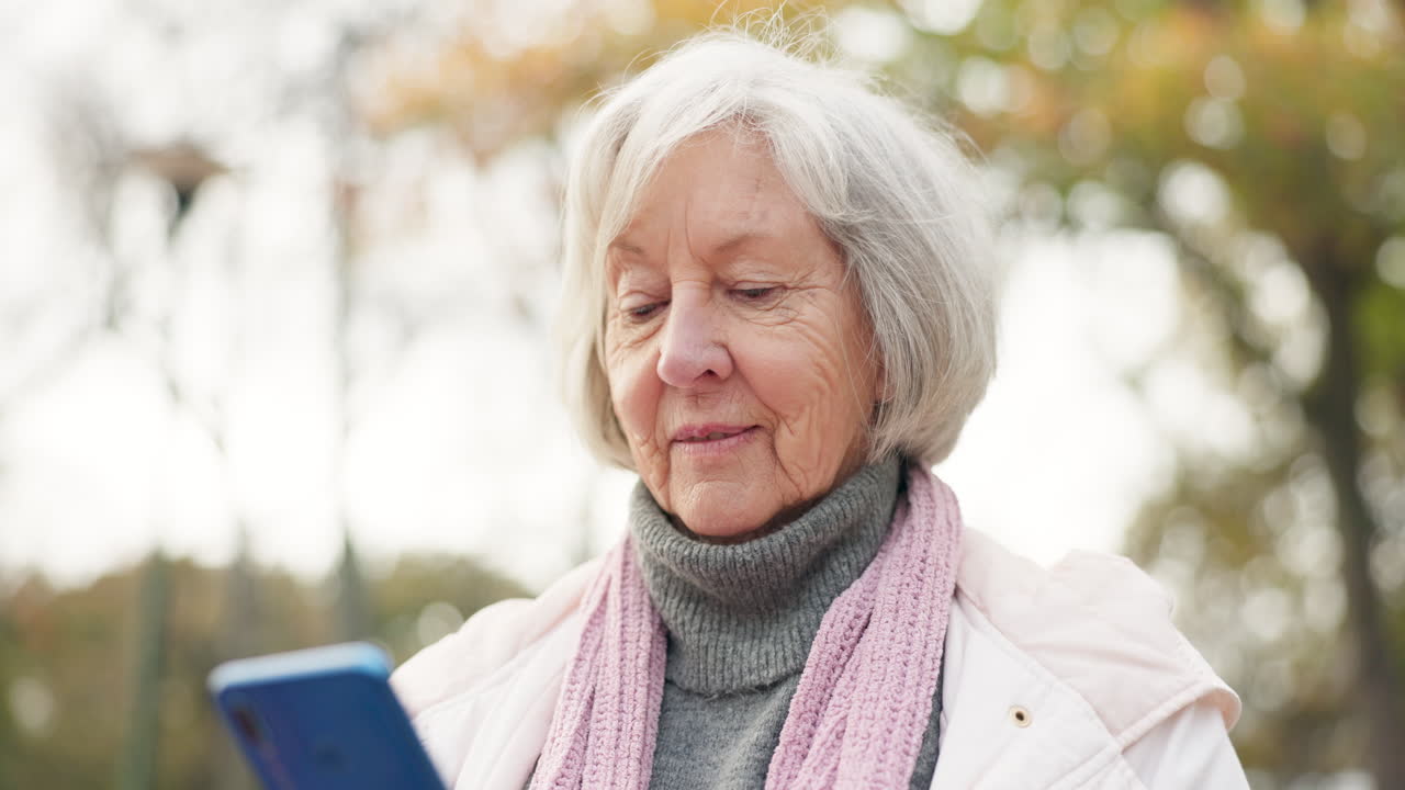 공원에서 스마트폰을 사용하는 고령 여성