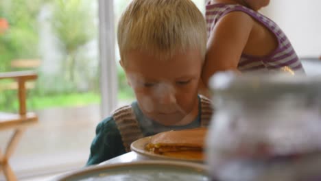 siblings looking at pancakes on dining table 4k