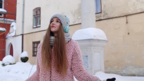 girl tourist during her vacation listening to music via headphones and dancing in old city center