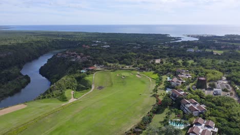 Vista-Aérea-Del-Paisaje-De-Drones-De-Un-Campo-De-Golf-Y-Un-Resort-De-Lujo-Cerca-De-Un-Río,-República-Dominicana