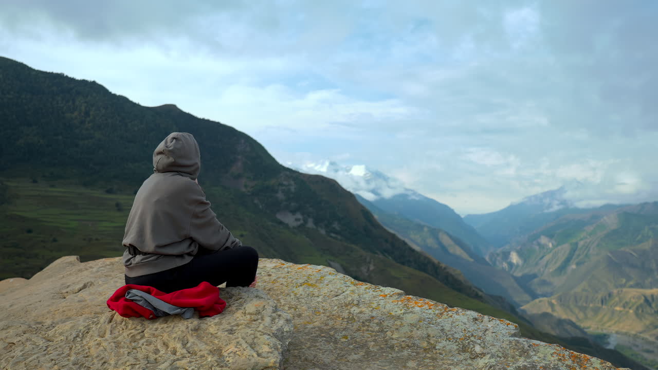 Bir dağ zirvesinde meditasyon yapan kişi