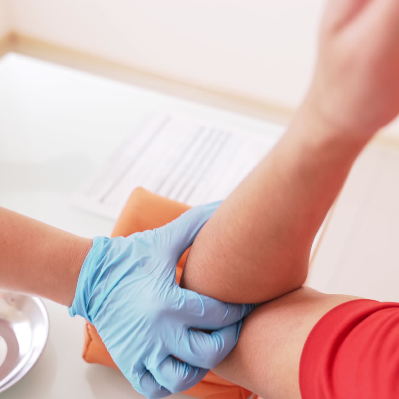 Process of taking a blood sample from vein. Hands of a nurse in blue gloves pricking a needle into a patient's vein. Medical assistant collecting blood from vein. Close-up.