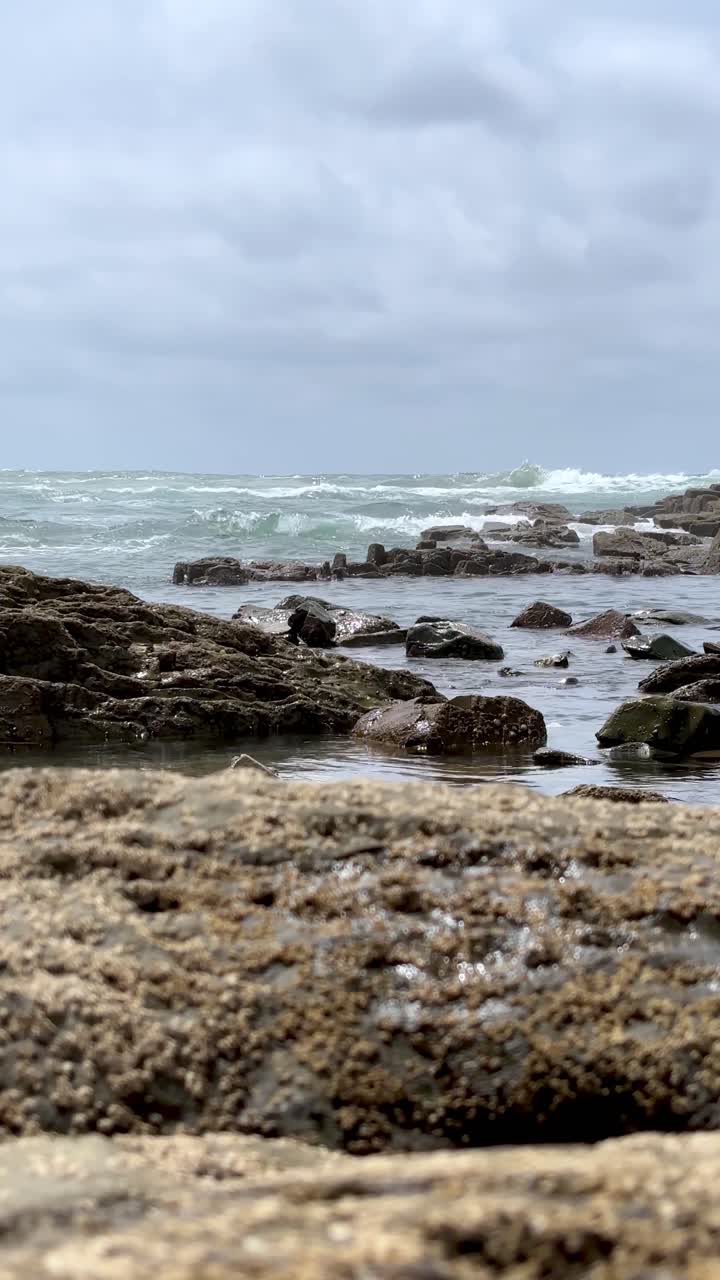 Relaxing ocean waves crash against rocky shore during cloudy day on Moroccan coast