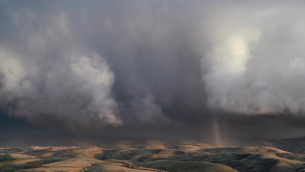 Dramatische Sturmwolken ziehen über sanften Hügeln auf
