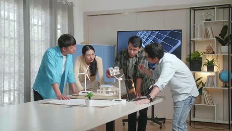 grupo de ingenieros asiáticos teniendo una reunión sobre el modelo de una casa pequeña con panel solar en la oficina