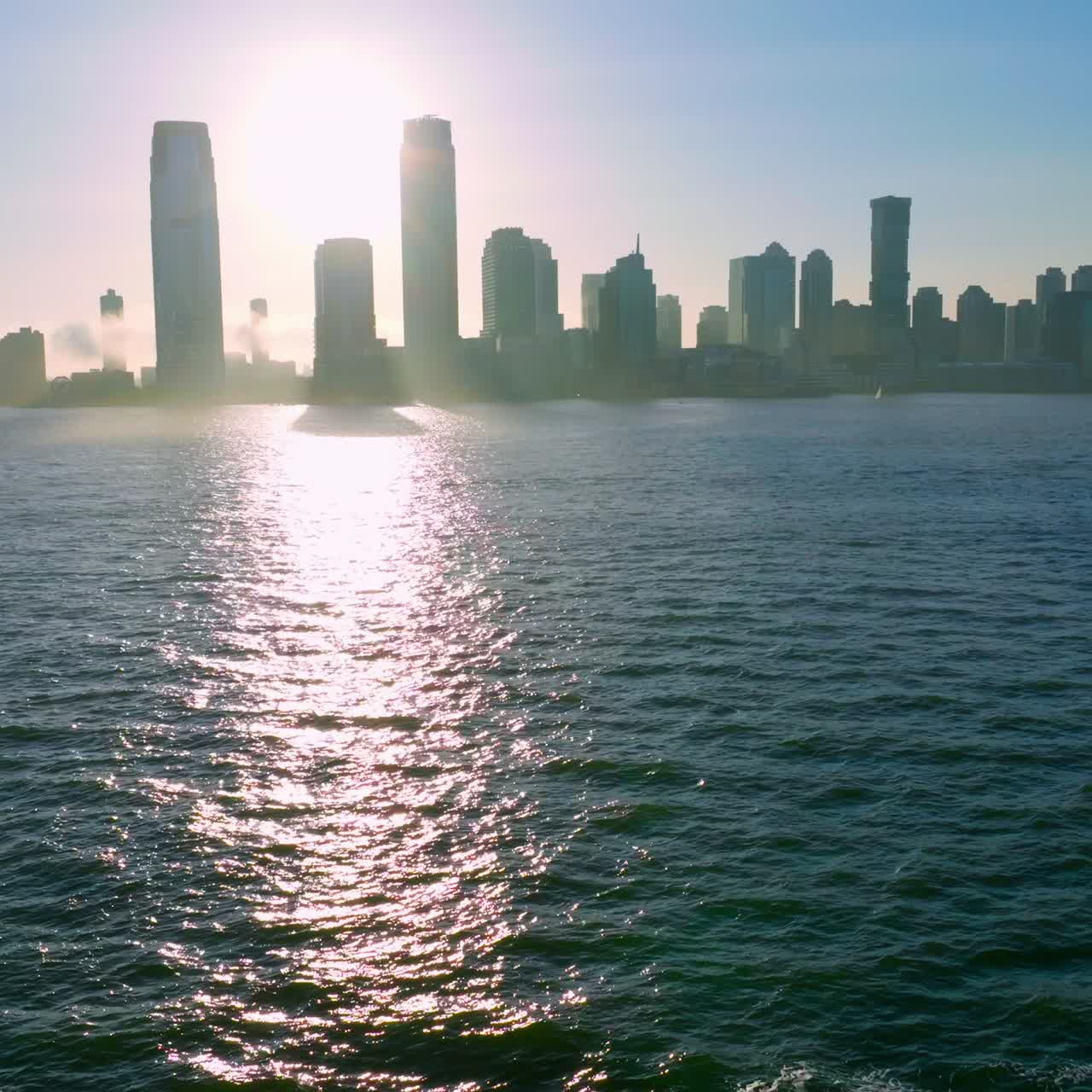Dark waters of East River with fantastic sun path on. Dark silhouette of skyscrapers towering over Manhattan Island
