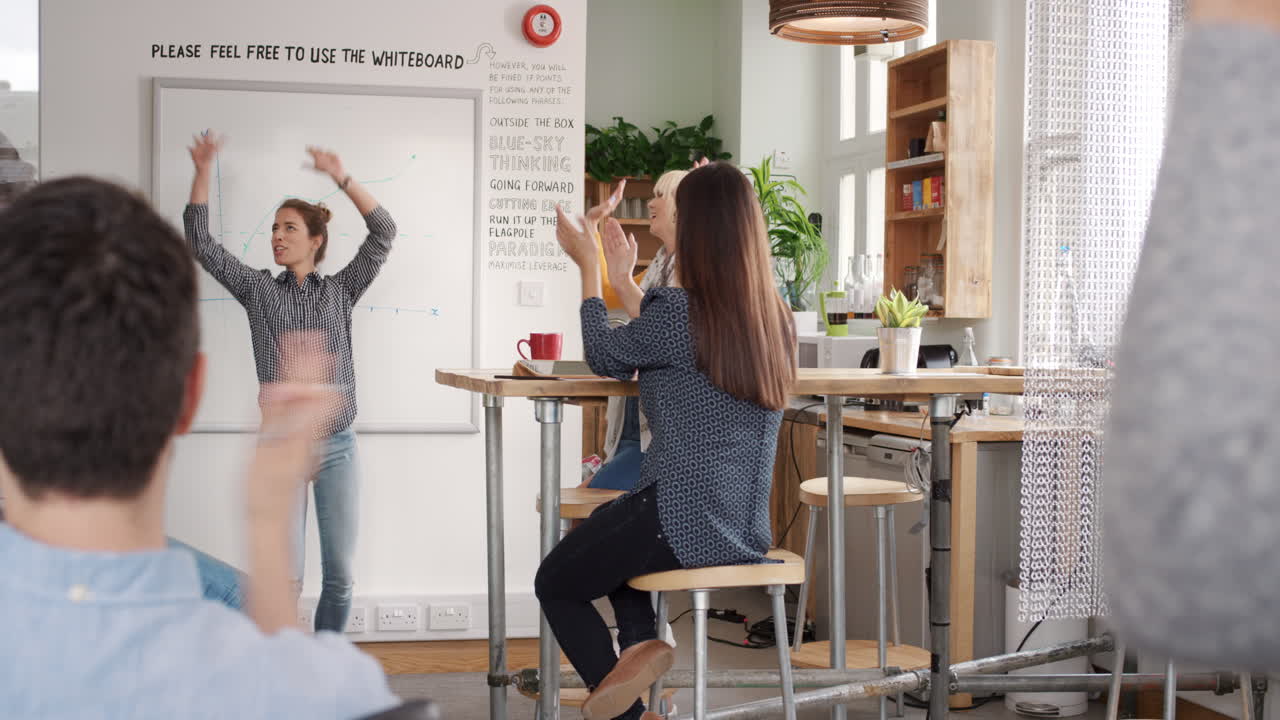 Crazy happy business woman dancing doing victory dance in team meeting celebrating success achievement