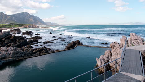 marine tide pool next to coastal walkway overlooking scenic breaking waves