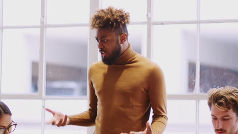 creativo masculino negro del milenio está evaluando a sus colegas sentados en una sala de reuniones, de cerca
