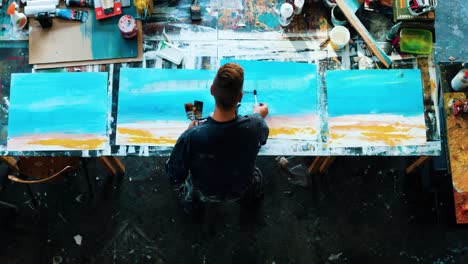 overhead shot of young male painter creating original artwork inside art studio - slow motion