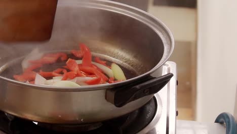 sauteing onions and red paprika on a hot pan, home cooking and candid daily life