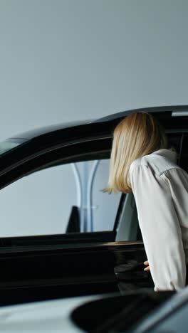 woman looking at a black suv in a car showroom