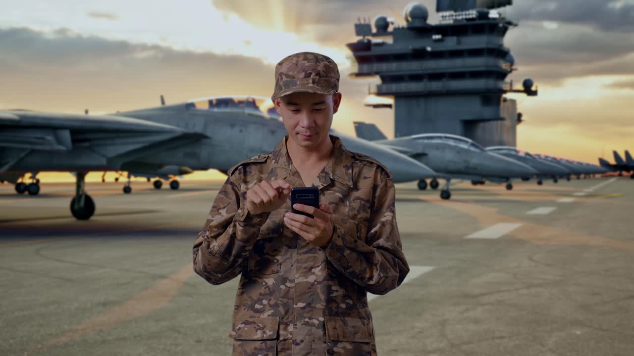 Military Personnel Using Smartphone on Aircraft Carrier Deck at Sunset