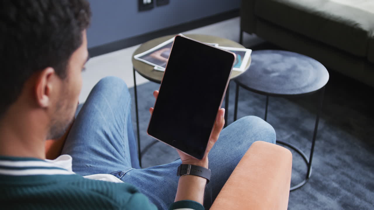 hombre de negocios biracial sentado usando una tableta digital en una oficina moderna