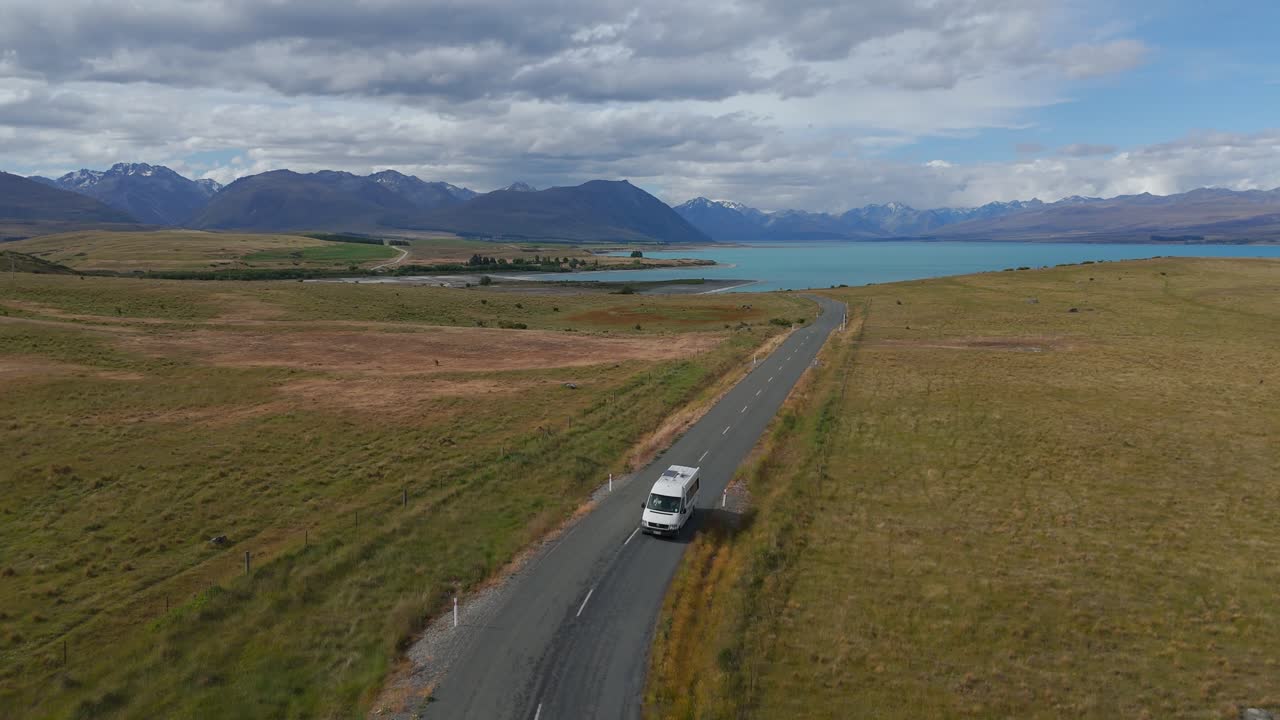 Yeni Zelanda'nın Manzaralı Güney Adası'ndaki Turkuaz Tekapo Gölü'nden ayrılan karavan.