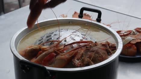 placing seafood river prawn blue crabs into hotpot ready to cook